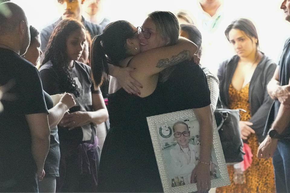 The mother of seven-year-old Larissa Maia Toldo, who was killed by a man with a hatchet inside a day care center, holds a photo of her daughter while she is comforted during Larissa's funeral at the Sao Jose cemetery, Blumenau, Santa Catarina state, Brazil, Thursday, April 6, 2023. A man with a hatchet jumped over a wall and burst into a day care center Wednesday in Brazil, killing four children, authorities said. (AP Photo/Andre Penner)