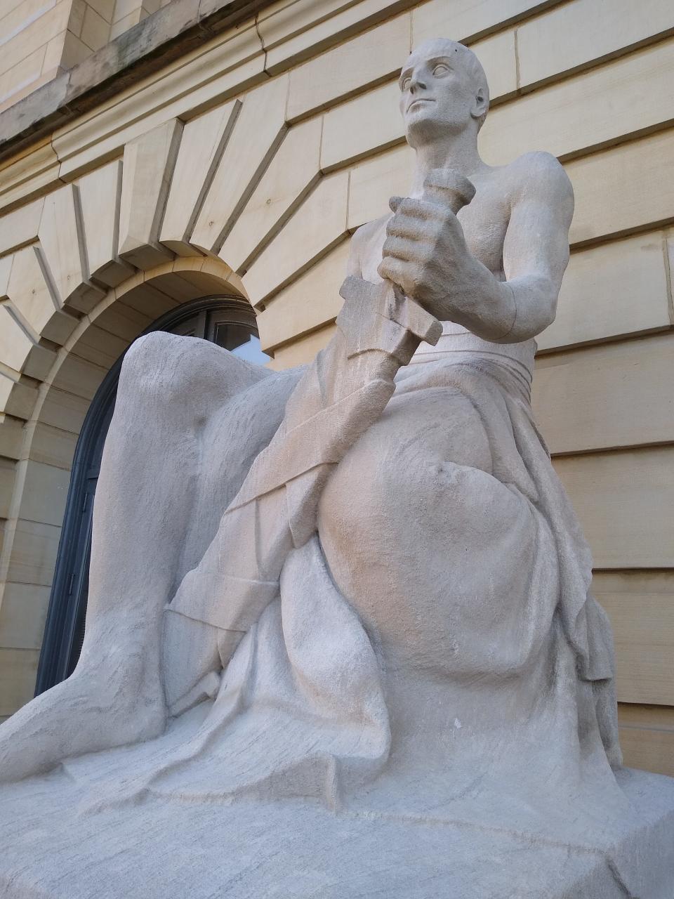 The limestone statue of “Justice,” carved by Herman N. Matzen, clutches a sword outside the Summit County Courthouse in downtown Akron.