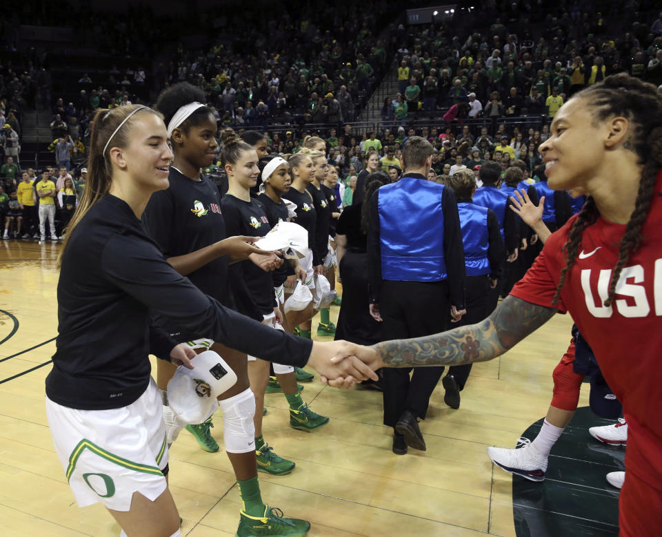 Oregon's Sabrina Ionescu, left, exchanges hats with U.S.'s Seimone Augustus before their women's exhibition basketball game in Eugene, Ore., Saturday, Nov. 9, 2019. (AP Photo/Chris Pietsch)