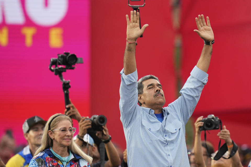 El presidente Nicolás Maduro, acompañado de la primera dama Cilia Flores, con los brazos levantados en el acto de cierre de campaña en Caracas, Venezuela, el jueves 25 de julio de 2024. Maduro busca la reelección para un tercer mandato en las elecciones del 28 de julio. (AP Foto/Fernando Vergara)