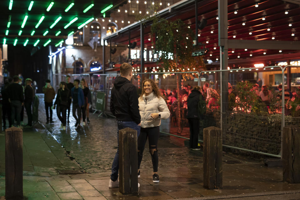 A view of people outside a bar after Prime Minister Boris Johnson laid out a new three-tier alert system for England, in Liverpool, England, Monday Oct. 12, 2020. The British government has carved England into three tiers of risk in a bid to slow the spread of a resurgent coronavirus. The northern city of Liverpool is in the highest category and will close pubs, gyms and betting shops. (AP Photo/Jon Super)