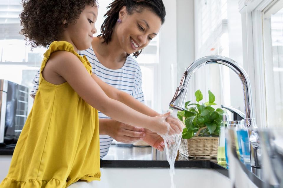 mother and daughter washing their hands at the kitchen sink using a low flow faucet