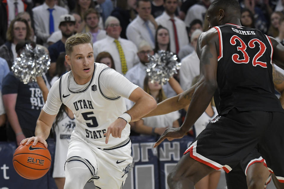 Utah State guard Sam Merrill (5) dribbles the ball as Fresno State forward Nate Grimes (32) defends during the first half of an NCAA college basketball game Saturday, Dec. 7, 2019, in Logan, Utah. (AP Photo/Eli Lucero)