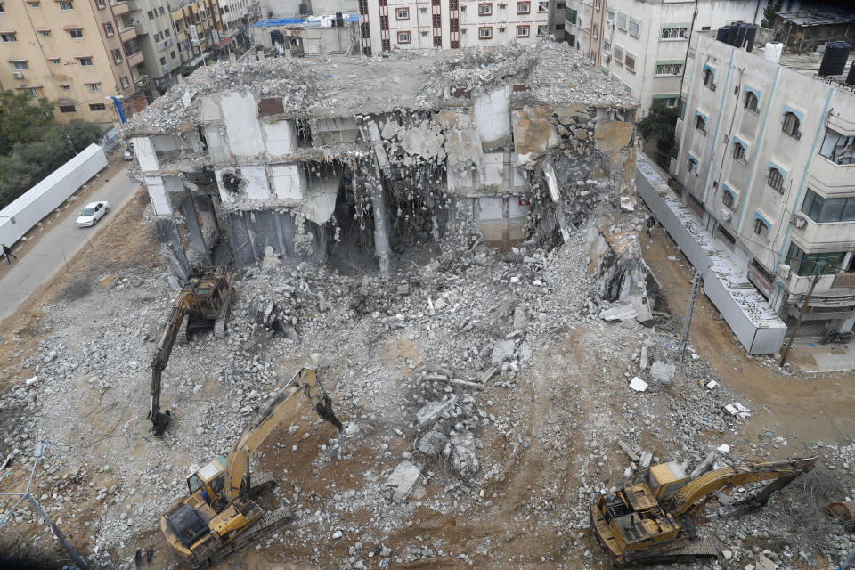 Palestinian workers use backhoes to break and remove parts of a building, which was damaged by Israeli airstrikes during Israel's war with Gaza's Hamas rulers last May, in the central al-Rimal neighborhood of Gaza City, Dec. 23, 2021. The Gaza Strip has few jobs, little electricity and almost no natural resources. But after four bruising wars with Israel in just over a decade, it has lots of rubble. Local businesses are now finding ways to cash in on the chunks of smashed concrete, bricks and debris left behind by years of conflict. (AP Photo/Adel Hana)