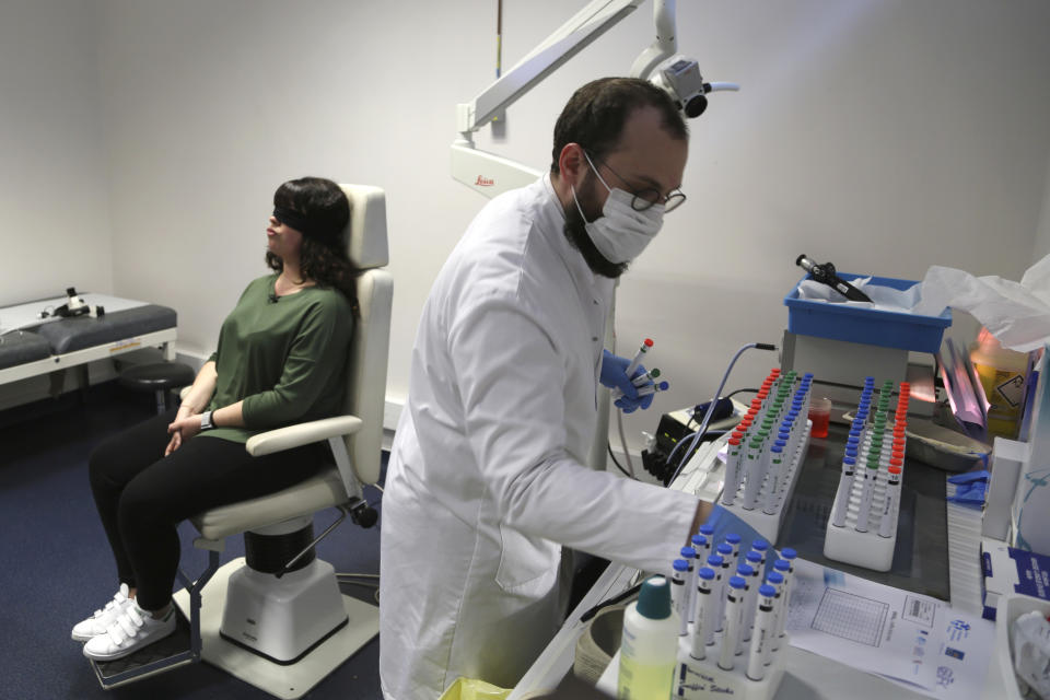 Dr. Clair Vandersteen, right, assembles tubes of odors to waft under the nose of a blindfolded patient, Gabriella Forgione, during tests in a hospital in Nice, France, on Monday, Feb. 8, 2021, to help determine why she has been unable to smell or taste since she contracted COVID-19 in November 2020. A year into the coronavirus pandemic, doctors and researchers are still striving to better understand and treat the accompanying epidemic of COVID-19-related anosmia — loss of smell — draining much of the joy of life from an increasing number of sensorially frustrated longer-term sufferers like Forgione. (AP Photo/John Leicester)