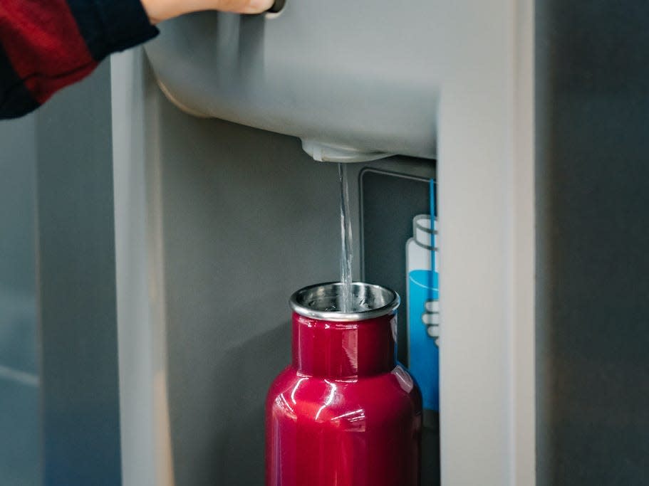 A person fills up their reusable water bottle at an airport.