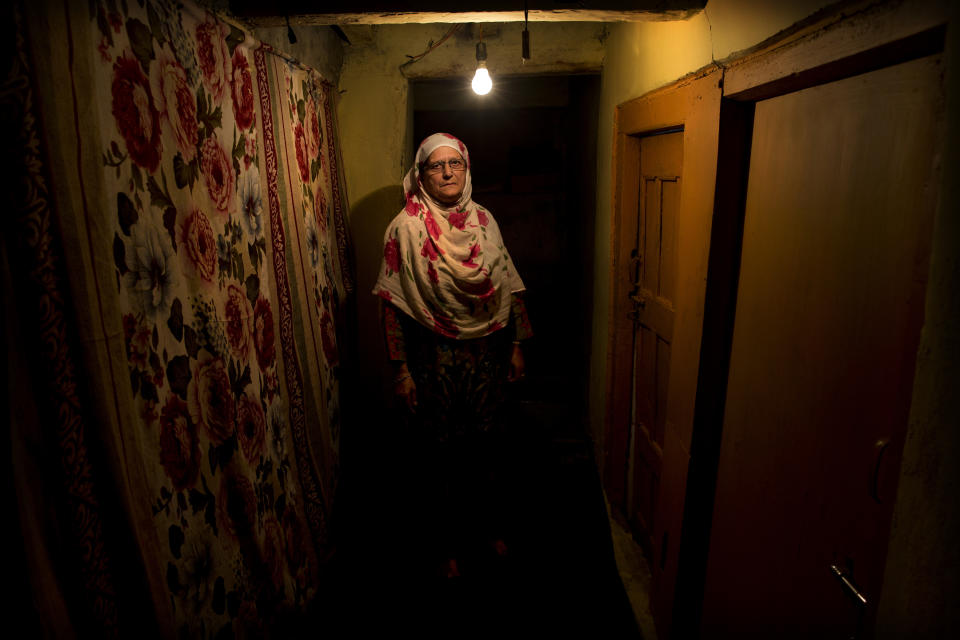 In this Sept. 25, 2019, photo, Ateeqa Begum, mother of a 22-year-old Kashmiri detainee Fasil Aslam Mir, stands for a photograph inside her house in Srinagar, Indian controlled Kashmir. Begum has lived alone ever since her only son Fasil, in his late twenties, was detained on his way home after fetching medicines for her. “My son has been shifted to a jail in an Indian city and I have no means to travel there to see him,” she said. (AP Photo/ Dar Yasin)