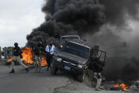 Police abandon their vehicle during a demonstration that turned violent in which protesters demanded justice for the assassinated President Jovenel Moise in Cap-Haitien, Haiti, Thursday, July 22, 2021. Demonstrations after a memorial service for Moise turned violent on Thursday afternoon with protesters shooting into the air, throwing rocks and overturning heavy concrete barricades next to the seashore as businesses closed and people took cover. (AP Photo/Matias Delacroix)