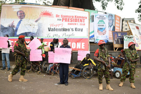 People hold signs asking for a re-count and credible elections near the high court in Freetown, Sierra Leone March 26, 2018. REUTERS/Olivia Acland