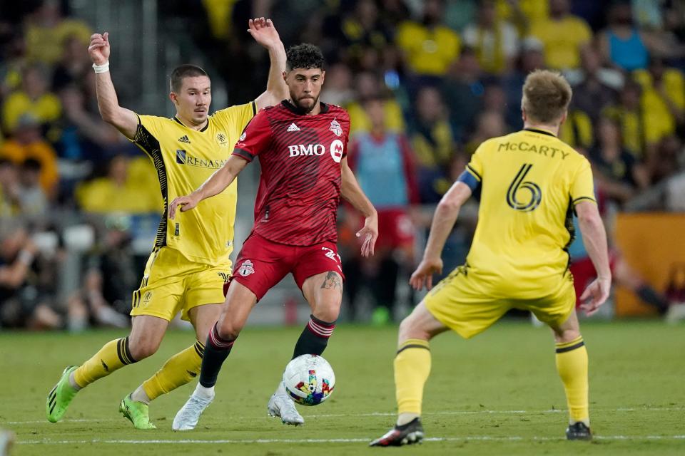 Toronto FC's Jonathan Osorio, center, dribbles between Nashville SC's Alex Muyl, left, and Dax McCarty (6) during the second half of an MLS soccer match Saturday, Aug. 6, 2022, in Nashville, Tenn. (AP Photo/Mark Humphrey)