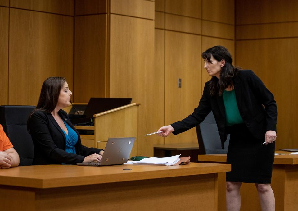 Assistant State Attorney Lauren Perry hands Assistant Public Defender Jane McNeill, attorney for Bryan James Riley, a copy of an interview during an evidentiary hearing in Bartow on Tuesday.