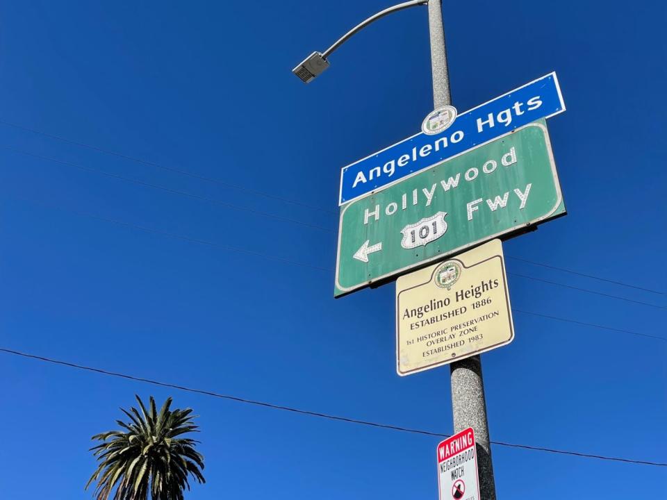 A blue city neighborhood sign spells out "Angeleno Hgts." The historic designator, however, spells it "Angelino Heights."