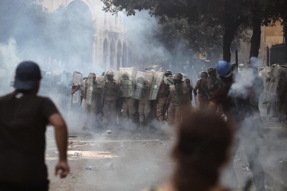 Lebanese soldiers stand among tear gas during clashes with protesters as part of a protest against the political elites and the government after this week's deadly explosion at Beirut port which devastated large parts of the capital in Beirut, Lebanon, Saturday, Aug. 8, 2020. (AP Photo/Thibault Camus)