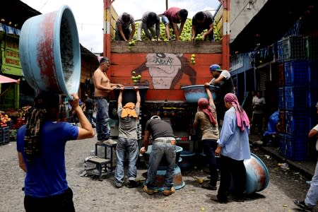 Workers unload oranges from a truck at La Terminal street market ahead of Sunday's presidential election in Guatemala City