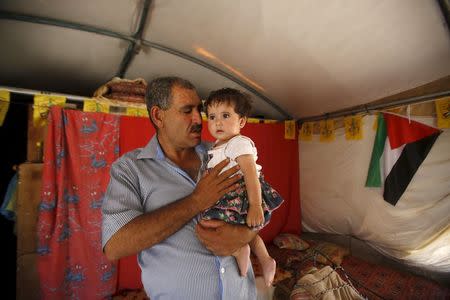 Palestinian man Jihad Nuwaja holds his granddaughter inside his tent in Susiya village, south of the West Bank city of Hebron July 20, 2015. REUTERS/Mussa Qawasma