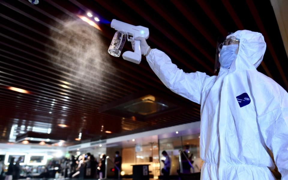 A staff member wearing protective suit disinfects a public bath - China News Service 