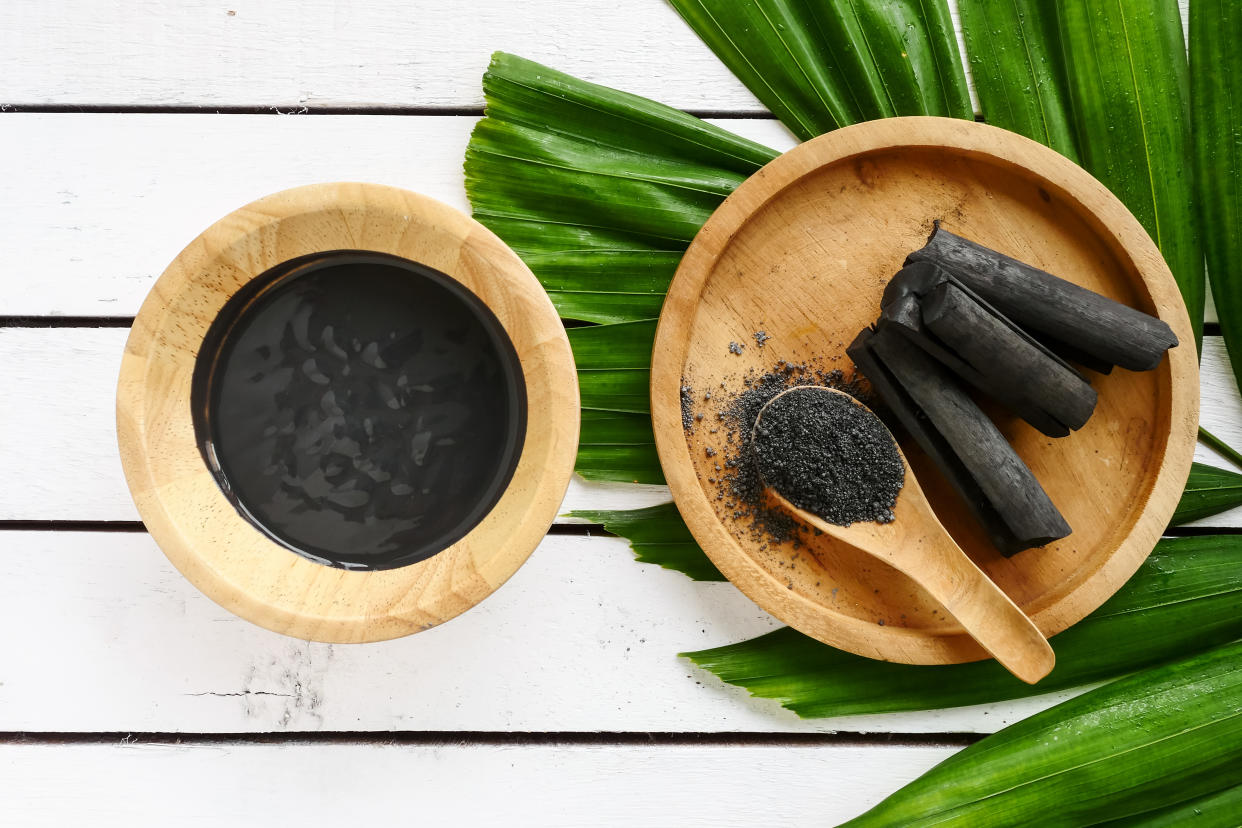 Facial mask and scrub by activated charcoal powder on wooden table