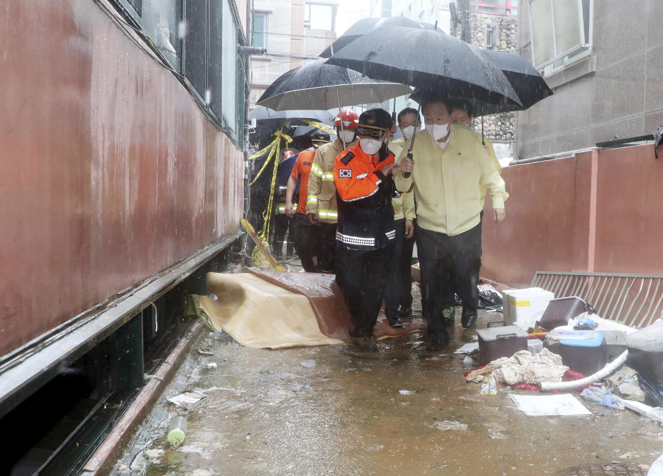 South Korean President Yoon Suk Yeol, right, looks around flood-damaged neighborhood in Seoul, South Korea, Tuesday, Aug. 9, 2022. Some of the heaviest rain in decades swamped South Korea's capital region, turning Seoul's streets into car-clogged rivers and sending floods cascading into subway stations. (Ahn Jung-won/Yonhap via AP)