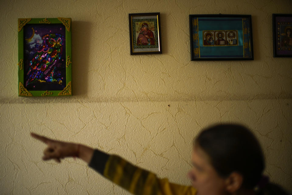 A resident points to her art work on a wall decorating her bedroom in a facility for people with mental and physical disabilities in the village of Tavriiske, Ukraine, Tuesday, May 10, 2022. The staff is faced with the dilemma of evacuating the facility, and how to do it with minimum disruption to the residents, some of whom have very severe disabilities and others for whom changes in environment can be disorientating and highly stressful. (AP Photo/Francisco Seco)