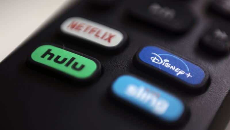 This 2020 photo shows logos for Netflix, Hulu, Disney Plus and Sling TV on a remote control in Portland, Ore. Disney has announced plans to buy up the remaining third of Hulu from telecomm/media giant Comcast.