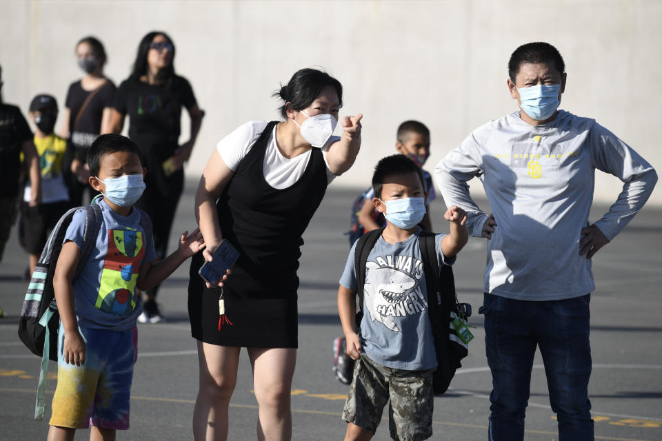 FILE - Masked parents direct their children on the first day of school at Enrique S. Camarena Elementary School, on July 21, 2021, in Chula Vista, Calif. The governors of California, Oregon and Washington have announced that schoolchildren will no longer required to wear masks starting March 12. The governors of the three states announced the measure in a joint statement as part of new indoor mask policies that come as coronavirus case and hospitalization rates decline across the West Coast. (AP Photo/Denis Poroy, File)