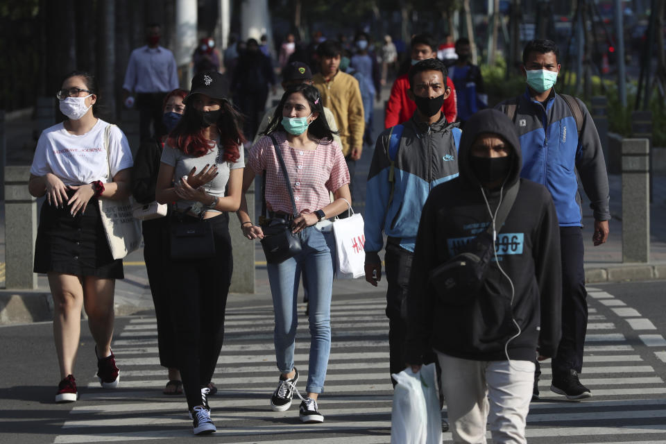 People wearing face masks as a precaution against the new coronavirus walk on a street in Jakarta, Indonesia, Tuesday, July 7, 2020. (AP Photo/Achmad Ibrahim)