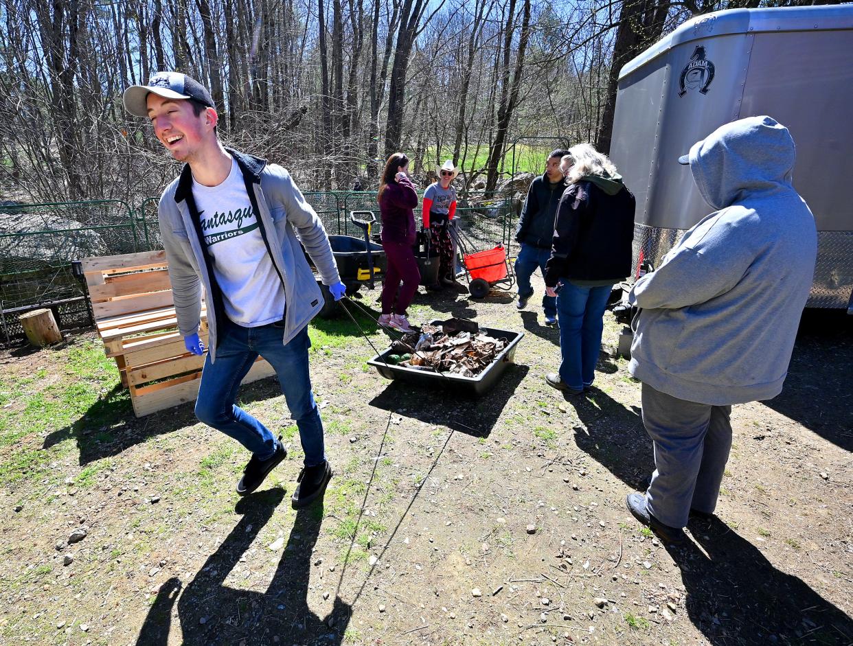 At an Earth Day event on a farm in Spencer Monday, Ethan Hillard, a job coach from the Center of Hope Foundation in Southbridge, pulls a bin full of trash collected by clients and staff from the center.