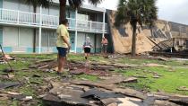 Residents of the Bogue Shores condominiums work to hook up a generator after the complex lost its roof during high winds from Hurricane Dorian in Atlantic Beach, N.C., on Friday, Sept. 6, 2019. Only a few residents stayed behind after an evacuation order and no one was injured. (AP Photo/Jeffrey Collins)