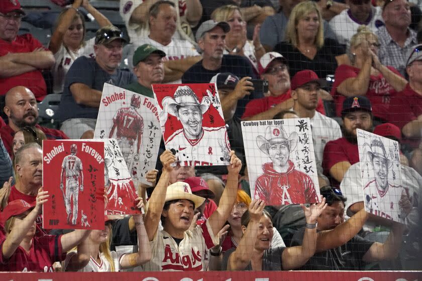 Fans hold up pictures of Los Angeles Angels' Shohei Ohtani and his interpreter Ippei Mizuhara.