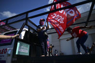 Former senator Miriam Ramírez de Ferrer carries a pro-Trump flag moments before leaving for the headquarters of the Republican party in support of President Donald Trump's candidacy a few weeks before the presidential election next November, in Carolina, Puerto Rico, Sunday, Oct. 18, 2020. President Donald Trump and former Vice President Joe Biden are targeting Puerto Rico in a way never seen before to gather the attention of tens of thousands of potential voters in the battleground state of Florida. (AP Photo/Carlos Giusti)