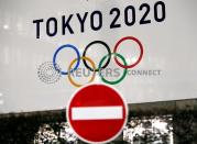 A banner for the upcoming Tokyo 2020 Olympics is seen behind a traffic sign in Tokyo, Japan