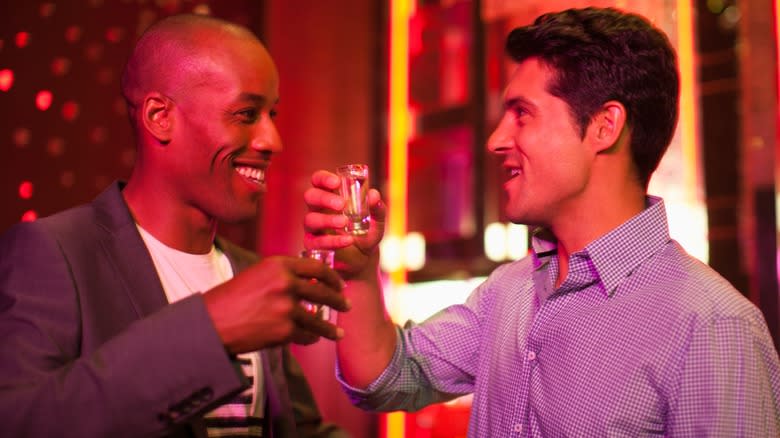 Two people smiling and toasting shots