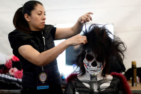 A woman gets a make-up before taking part in a procession to commemorate Day of the Dead in Mexico City, Mexico, October 28, 2017. REUTERS/Edgard Garrido