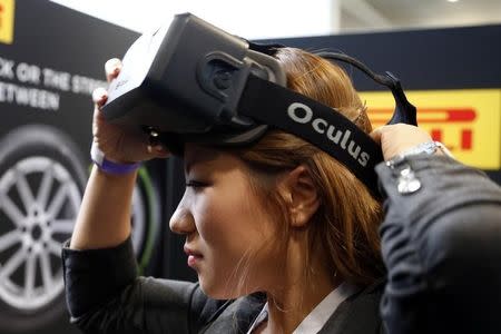 A woman puts on an Oculus virtual reality headset during preparations for the 2014 LA Auto Show in Los Angeles, California November 18, 2014. REUTERS/Lucy Nicholson