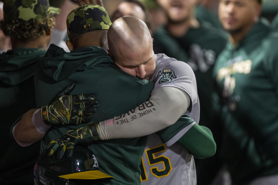 Oakland Athletics' Seth Brown, right, gets a hug in the dugout hitting a two-run home run against the Los Angeles Angels during the fifth inning of a baseball game in Anaheim, Calif., Friday, May 20, 2022. (AP Photo/Alex Gallardo)