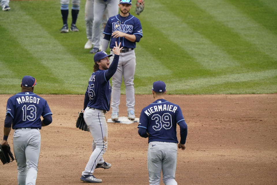 Tampa Bay Rays outfielder Brett Phillips (35) signals three wins after the Rays defeated the New York Yankees in three baseball games in a row Sunday, April 18, 2021, at Yankee Stadium in New York. Rays right fielder Manuel Margot (13) and center fielder Kevin Kiermaier (39) run toward the mound to celebrate. (AP Photo/Kathy Willens)