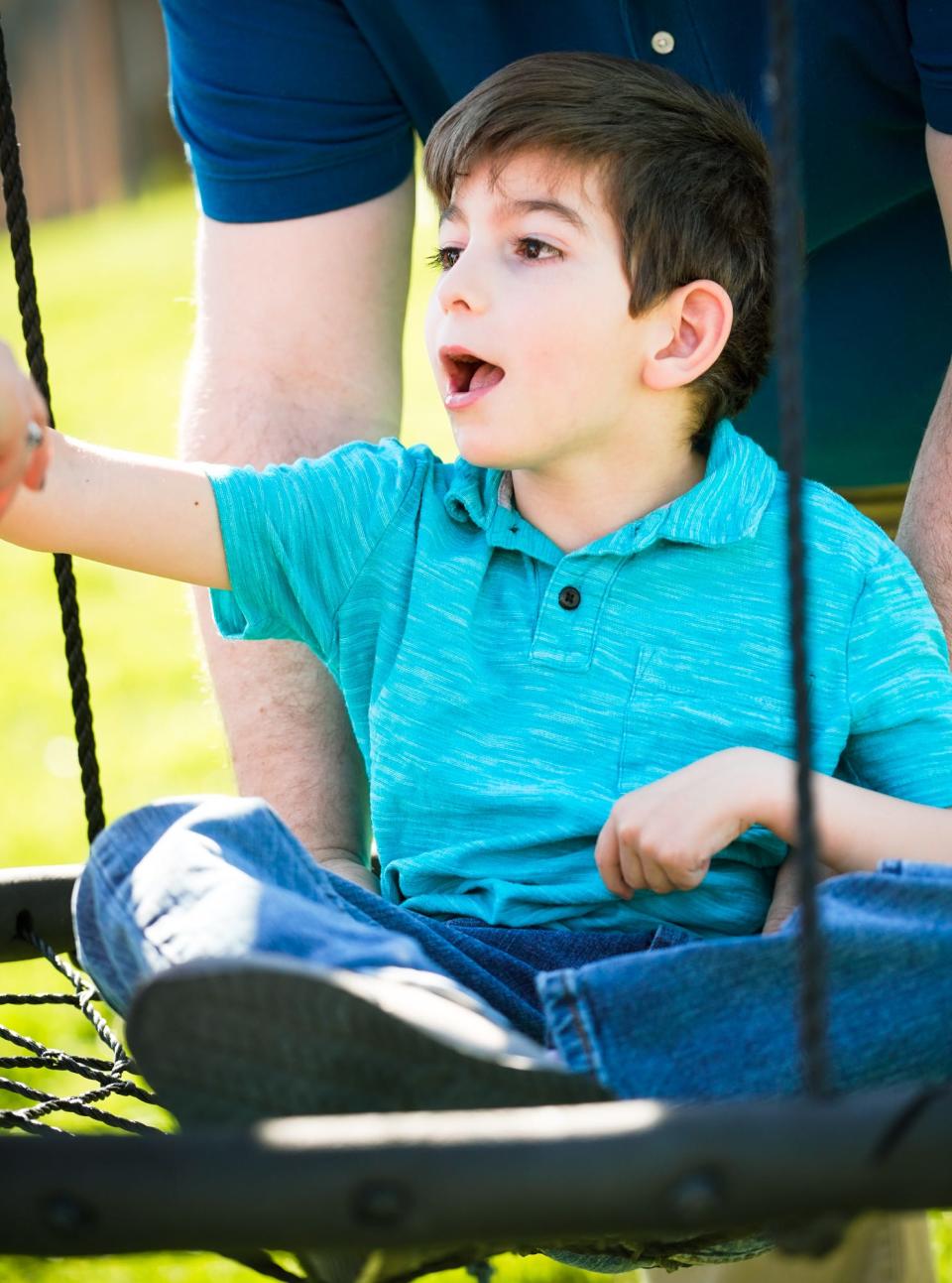 Ryder Harris plays on his home swing set with the assistance of his father Chris Harris, on Thursday, April 13, 2023 in Indiana. Ryder has a lifelong disorder called Polymicrogyria (PMG,) and epilepsy. The Harris family hopes a service dog would help to predict Ryder's seizures. 