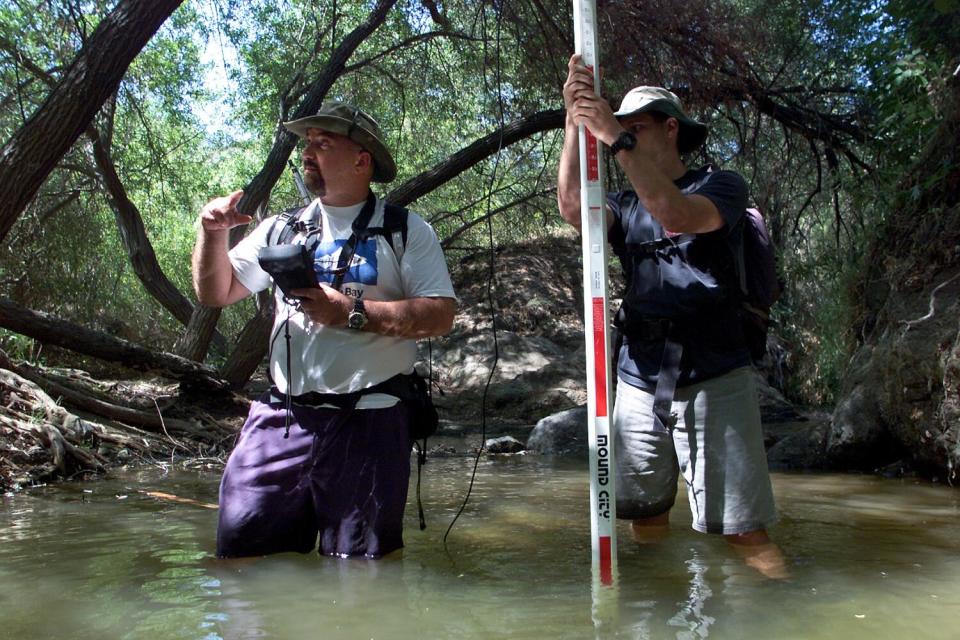 Mark Abramson and another man stand knee-deep in a Malibu creek.