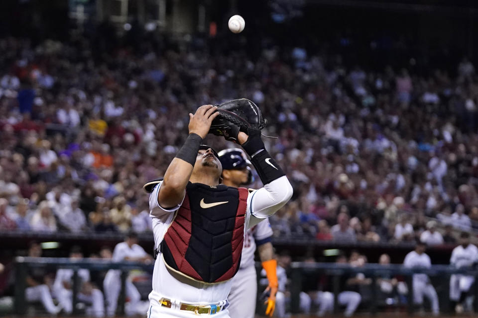 Arizona Diamondbacks catcher Gabriel Moreno, front, makes a catch on a bunt attempt by Houston Astros' Martin Maldonado, back, during the third inning of a baseball game, Saturday, Sept. 30, 2023, in Phoenix. (AP Photo/Ross D. Franklin)