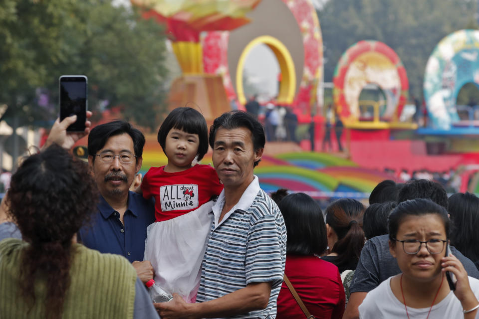Residents take a souvenir photo with a float stop along the Jainguomenwai Avenue in preparation for the parade for the 70th anniversary of the founding of the People's Republic of China, in Beijing, Tuesday, Oct. 1, 2019. (AP Photo/Andy Wong)