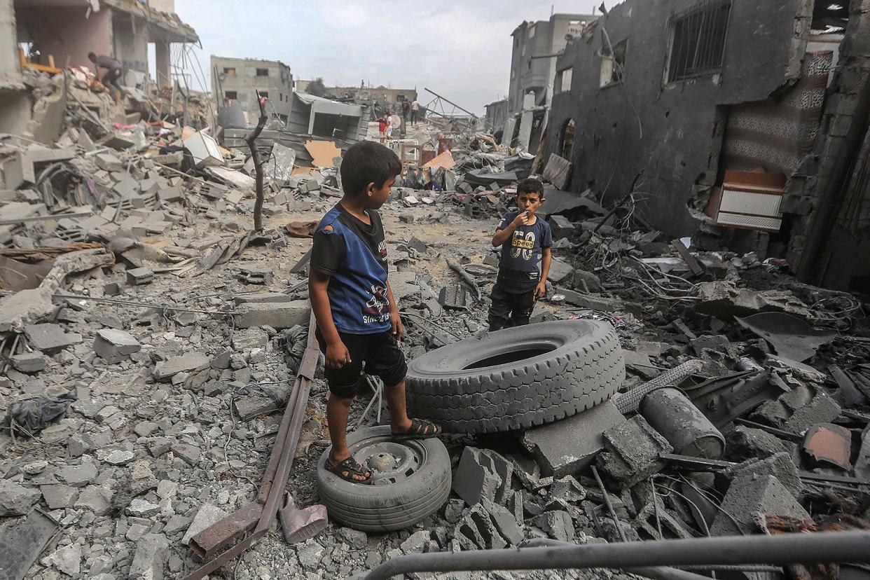 Two young boys stand between ruined buildings.