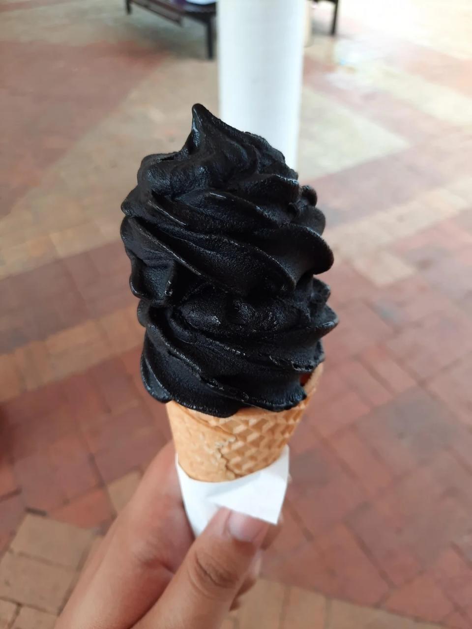 Person holding a cone with black ice cream