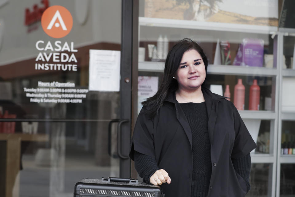 In this Friday, May 8, 2020 photo, Christa Schall poses outside her cosmetology school, Casal Aveda Institute, in Austintown, Ohio. More than 8 million students in the U.S. are enrolled in technical colleges, seeking certification in skilled trades like welding, phlebotomy and cosmetology. But unlike students at traditional colleges, their learning can't easily translate into Zoom courses, they learn through hands-on demonstrations. Now, many are eager to get back into the classroom, and some are reeling because they won't get to graduate on time. (AP Photo/Tony Dejak)