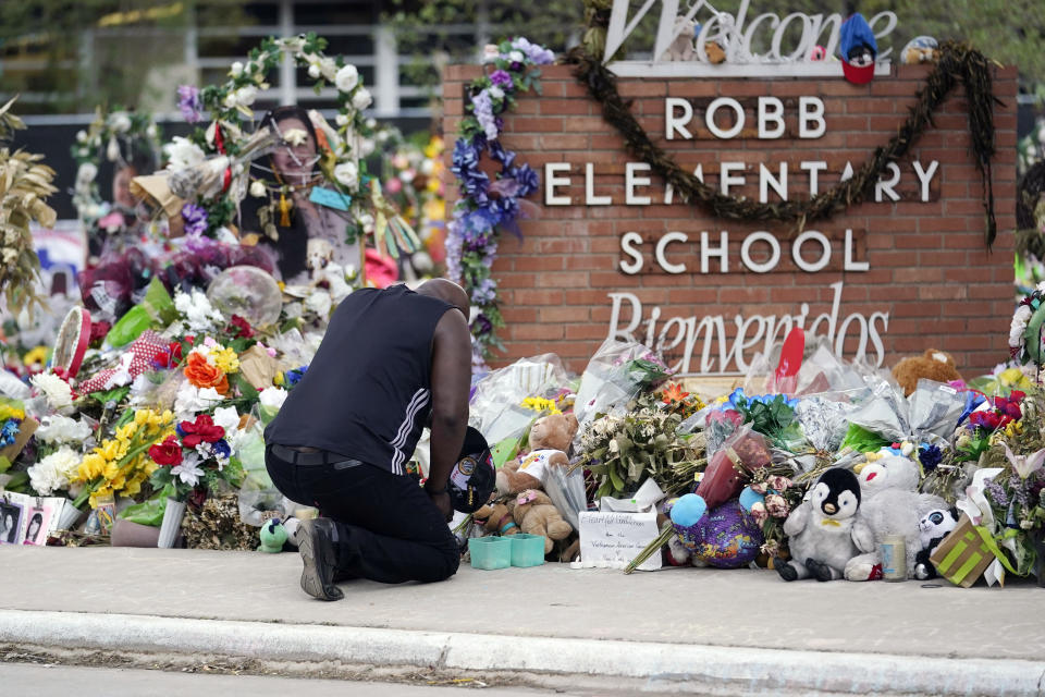 FILE - Reggie Daniels pays his respects a memorial at Robb Elementary School on June 9, 2022, in Uvalde, Texas. Nearly 400 law enforcement officials rushed to the mass shooting that left 21 people dead at the elementary school but “systemic failures” created a chaotic scene that lasted more than an hour before the gunman was finally confronted and killed, according to a report from investigators released Sunday, July 17, 2022. (AP Photo/Eric Gay, File)