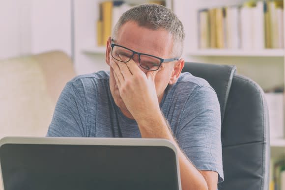 Man at laptop rubbing his eyes