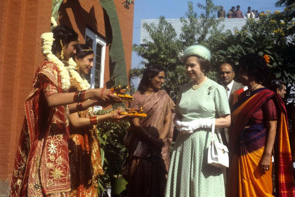 <p>The Queen is offered food by girls in traditional Indian dress at the Mahatma Gandhi memorial at Raj Ghat, Delhi. (PA Archive) </p>