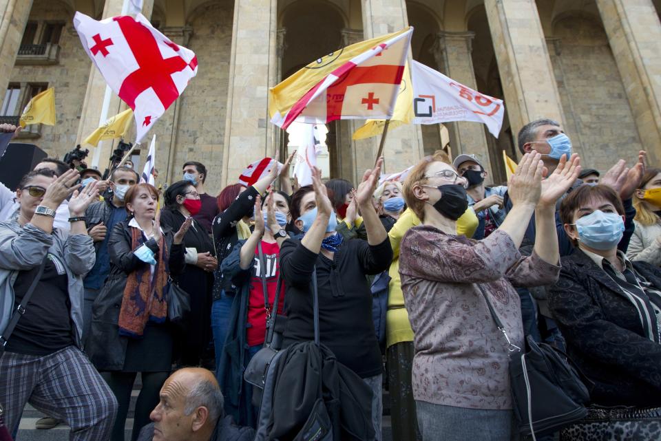 Supporters of the ex-President Mikhail Saakashvili's United National Movement, most of them wearing face masks to help curb the spread of the coronavirus, wave Georgian national and movement flags during rally to protest the election results, in front of the parliament's building in Tbilisi, Georgia, Sunday, Nov. 1, 2020. Preliminary election results show that Georgia's ruling party won the country's highly contested parliamentary election, but the opposition have refused to recognize Sunday's results. (AP Photo/Shakh Aivazov)