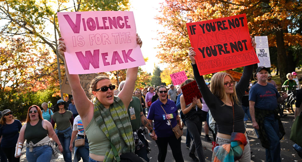 Two women hold up signs at a march against gendered violence.