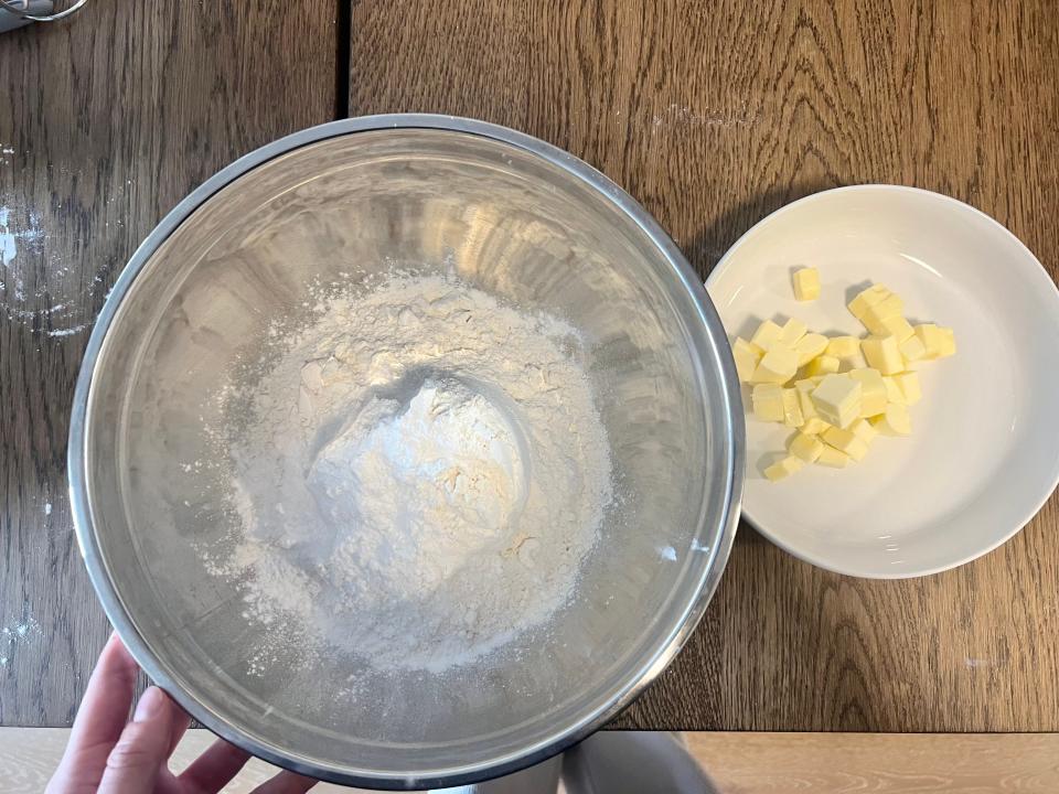 Adding small chunks of unsalted butter into the bowl.