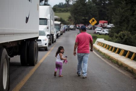 People walk along a blockade by members of the Supreme Indigenous Council of the entry to their community to avoid the installation of polling stations for Mexico's general election in the indigenous Purepecha town of Zirahuen, in Michoacan state, Mexico June 28, 2018. Picture taken June 28, 2018. REUTERS/Alan Ortega